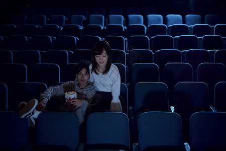 喋喋休的人幸福站立玩观看电影的观众在电影院背景