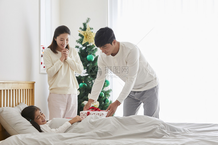 父母准备圣诞节礼物给床上的女儿图片