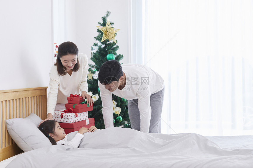 父母准备圣诞节礼物给床上的女儿图片