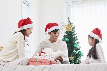 床上拆圣诞礼物开心的一家人图片