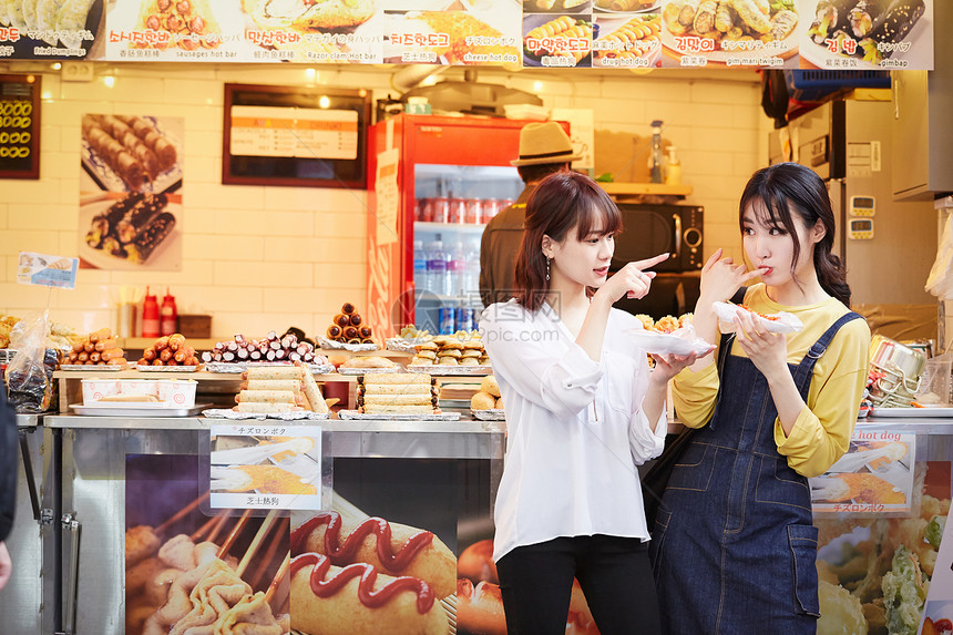 年轻女闺蜜一起逛美食街品尝美食图片