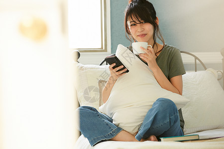 居家看手机喝咖啡的女青年图片