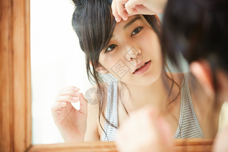 镜子前整理发型的年轻女子图片