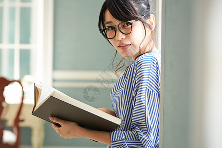 窗边阅读放松的年轻女子背景图片