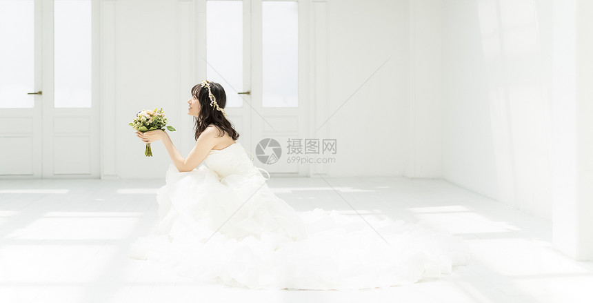 新娘拿着手捧花蹲坐在地上图片
