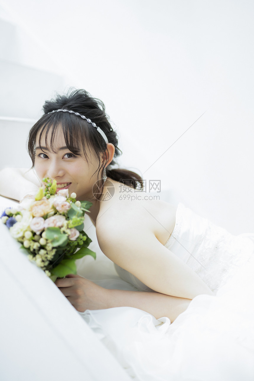 趴在台阶上拿着捧花的婚纱美女图片