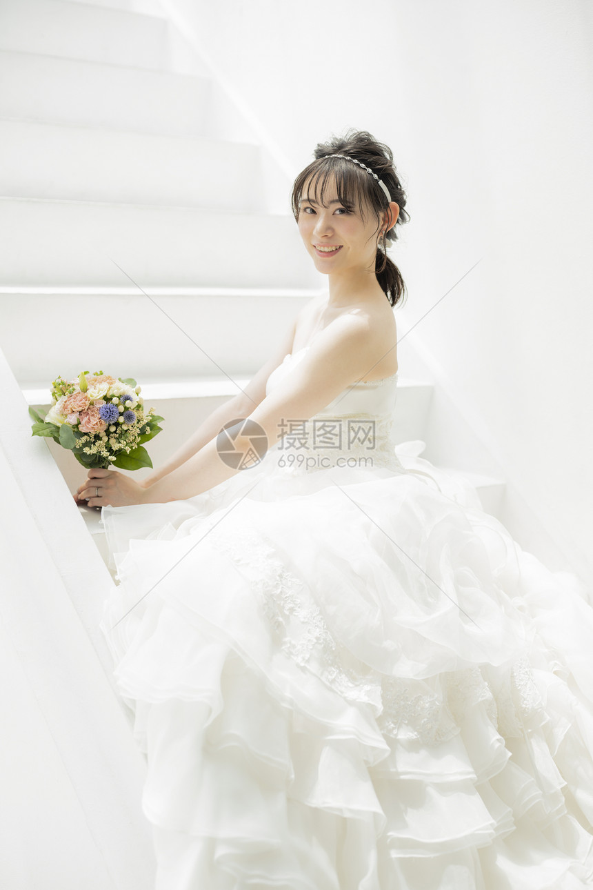 台阶上穿着婚纱拿着手捧花的女子图片
