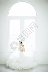 窗边穿着婚纱祈祷的女子图片