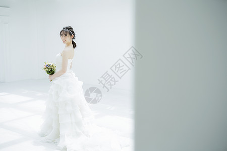 年轻女子穿着纯白的婚纱拿着手捧花背景图片
