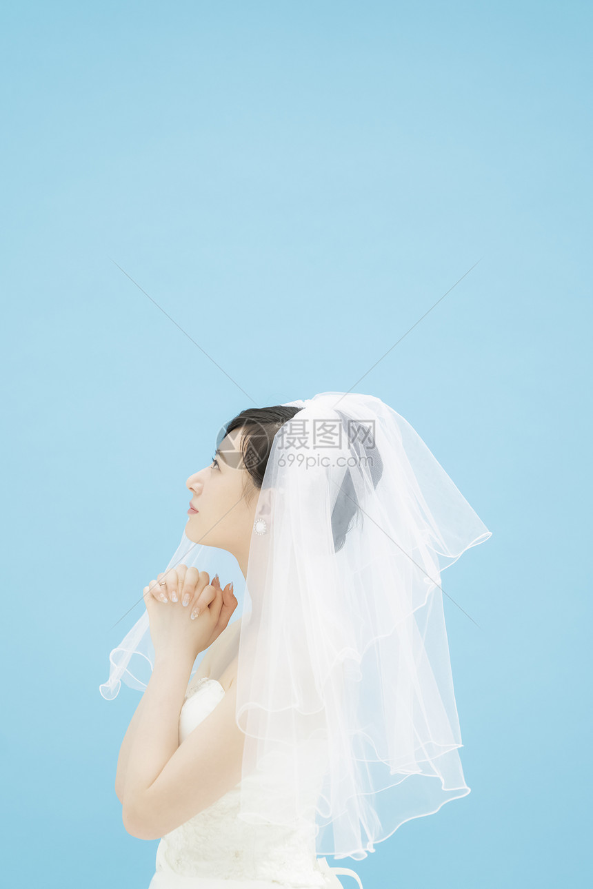 戴着头纱握紧双手祈祷的婚纱美女图片