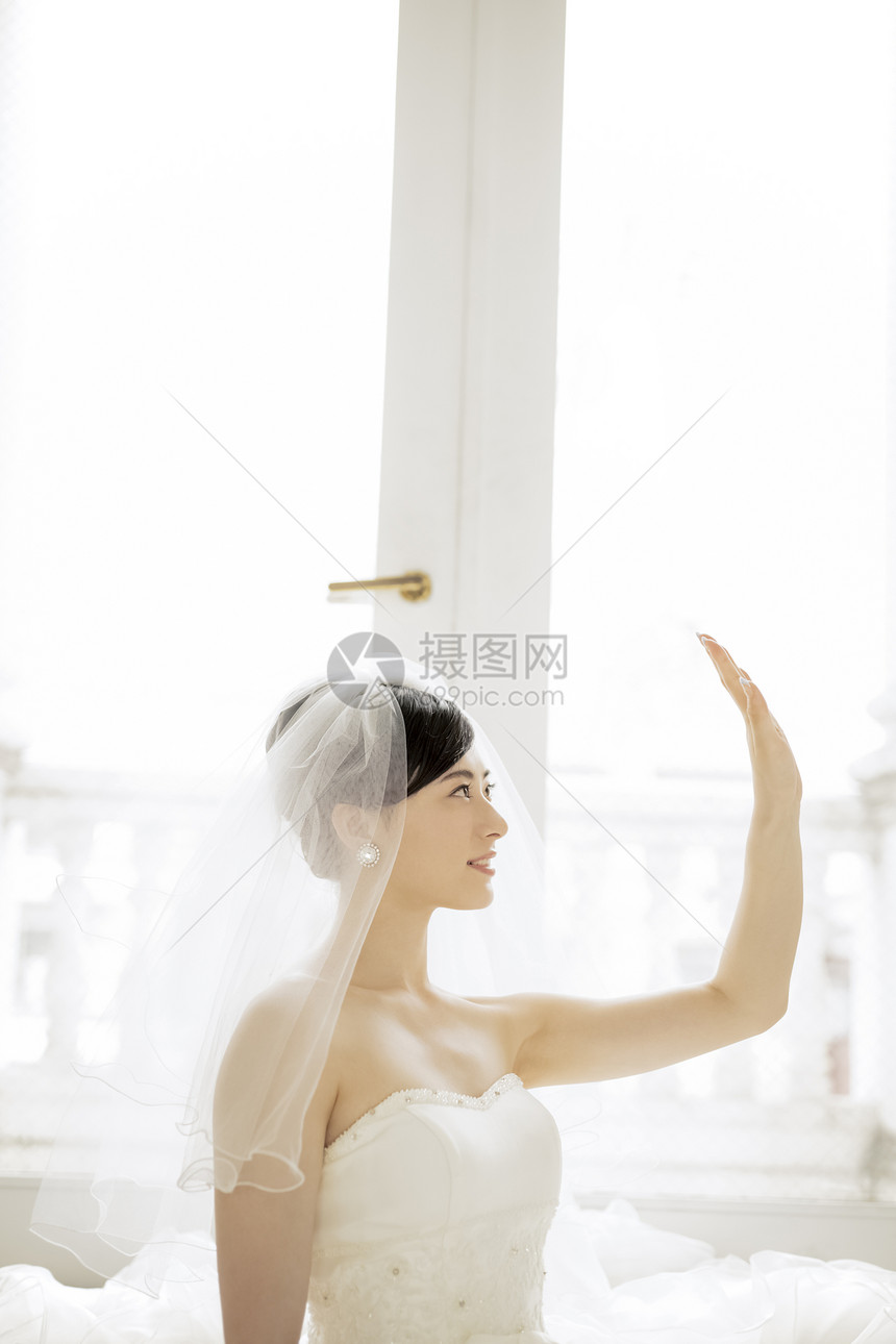 抬手挡阳光的婚纱美女图片