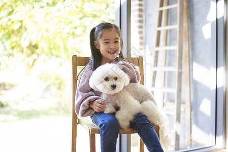 小朋友抱着宠物狗坐在椅子上图片