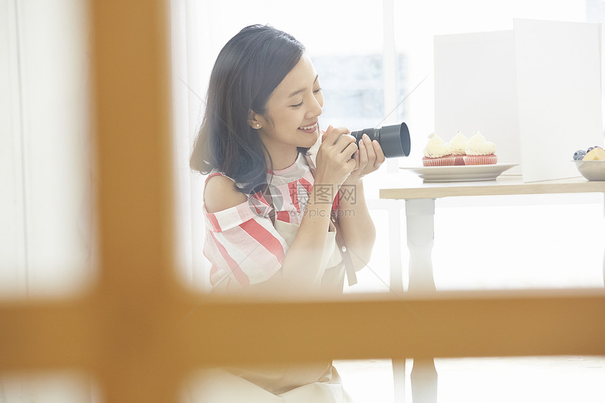 年轻女子拿着相机拍纸杯蛋糕图片