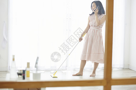 居家打扫卫生接听电话的年轻女子图片