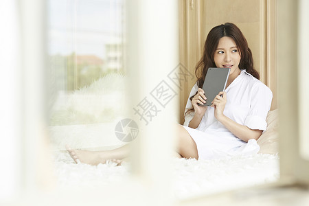 坐在床上拿着平板电脑的女青年图片