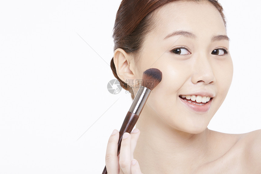 年轻女子使用化妆刷图片