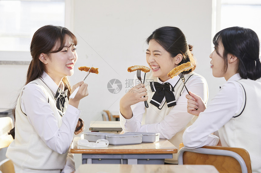 在教室的座位上吃午饭的女学生图片