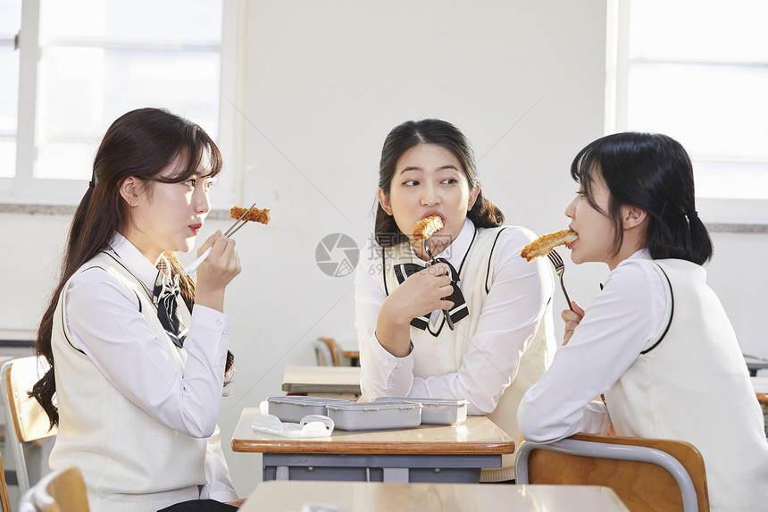 在教室的座位上吃午饭的女学生图片