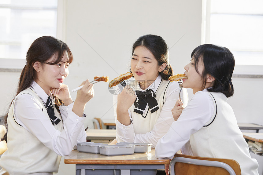 在教室的座位上吃午饭的女学生图片