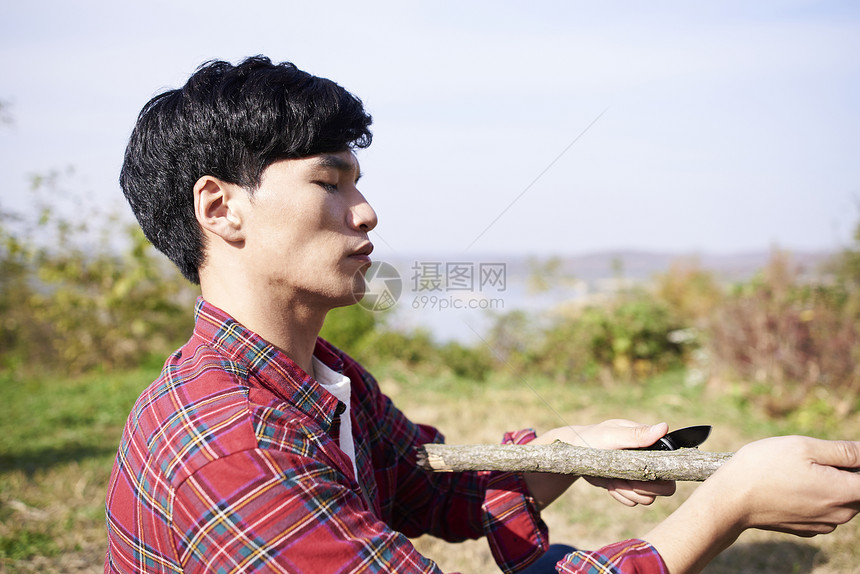 露营削树枝的年轻人图片