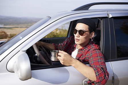 愉快旅行车上戴太阳镜的年轻人喝茶图片