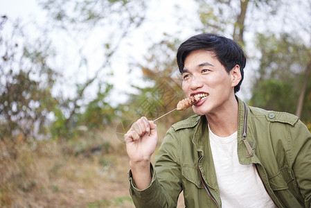 露营地吃烤串的男人图片