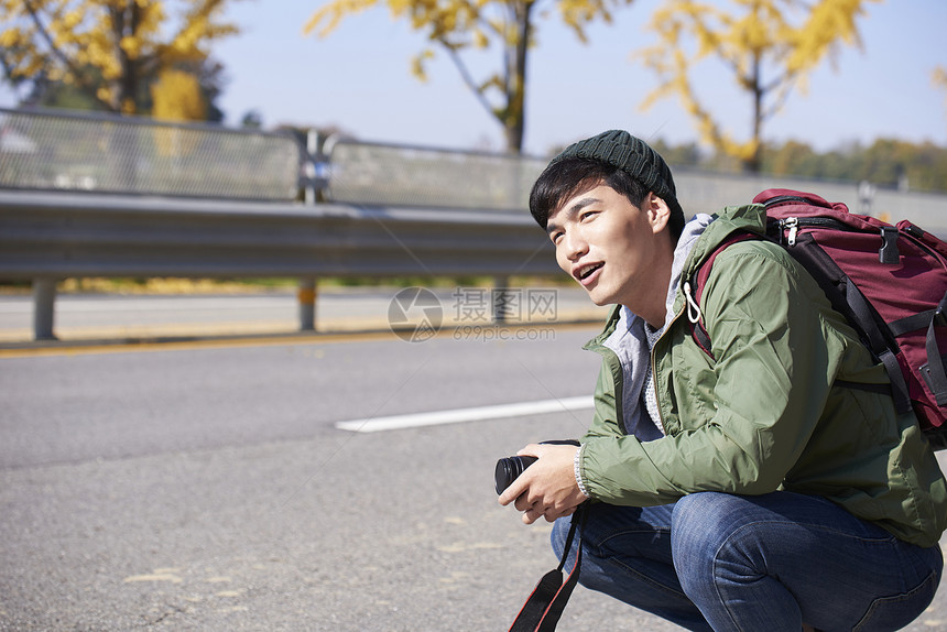 蹲在路边等车的青年男子图片