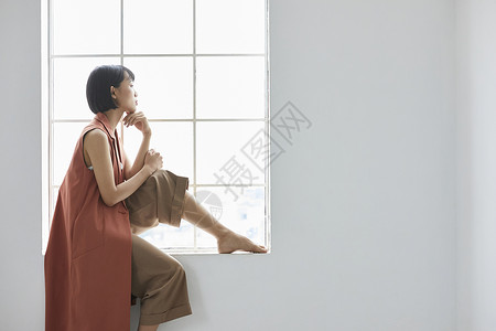 坐在窗边向外看的青年女子图片