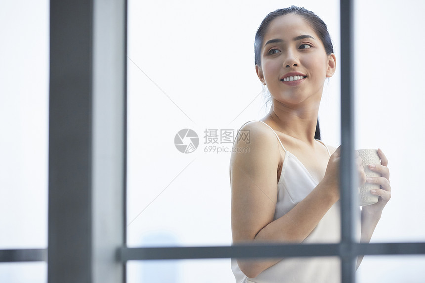 户外阳台捧着咖啡放松的年轻女子图片