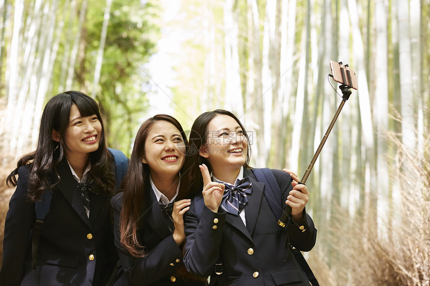 踏青健康游览三个高中女生在竹林的小直径采取自拍照图片