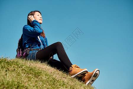 女人徒步旅行坐在草地上休息图片