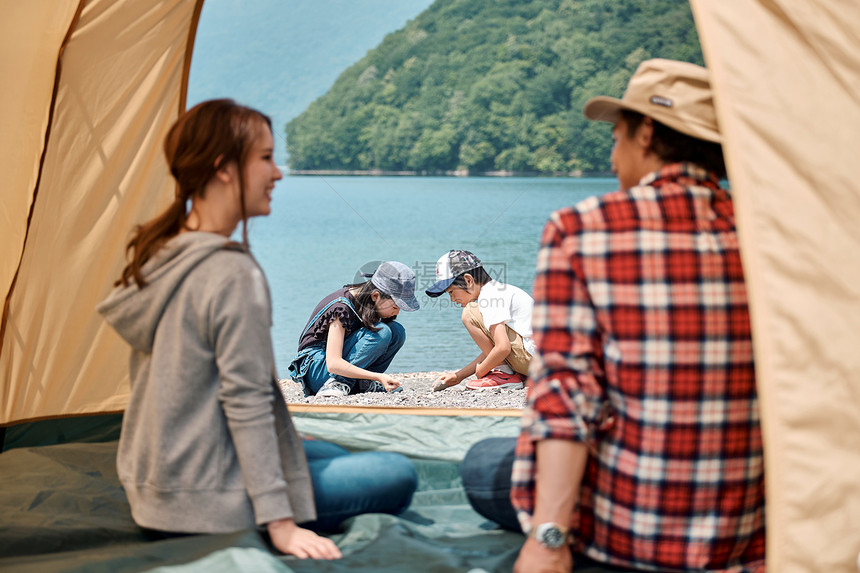 一家四口在野外湖边露营扎帐篷图片