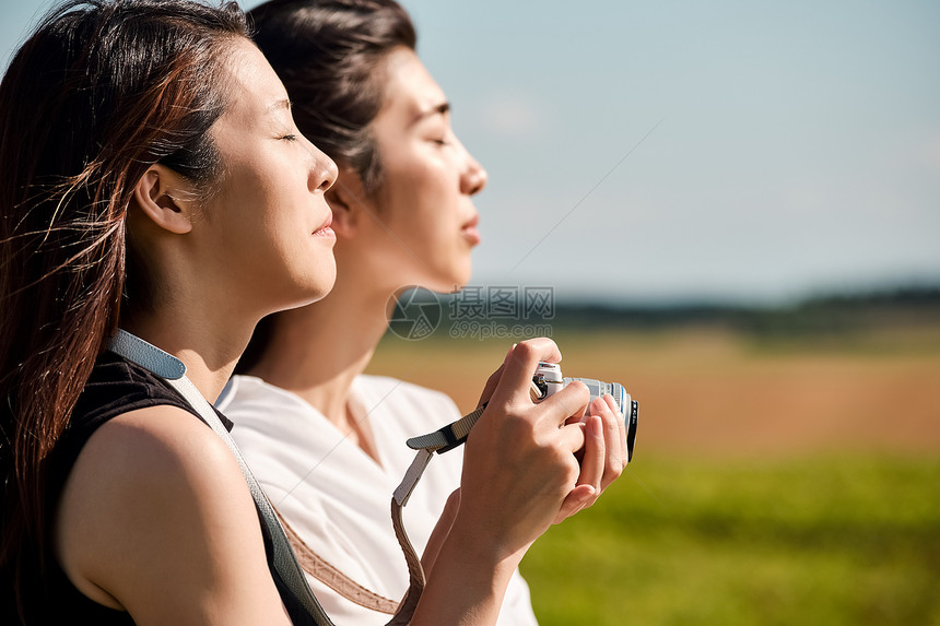 两个女人在户外开心用相机拍照图片