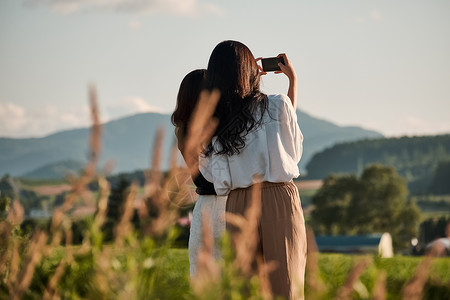 两个女人在户外开心用手机拍照图片