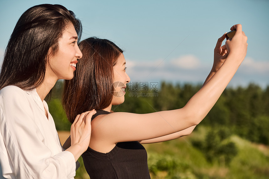 两个女人在户外开心用手机拍照图片