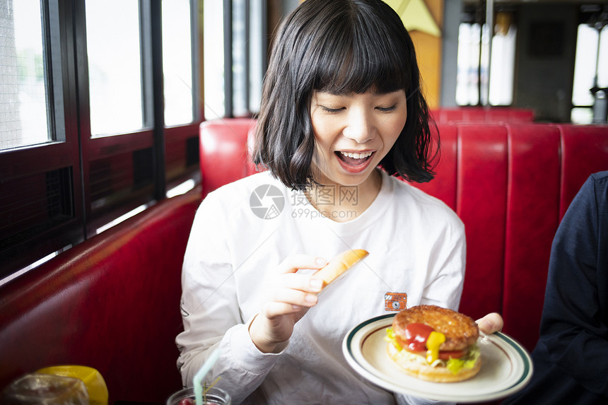 餐厅里吃汉堡的年轻女人图片