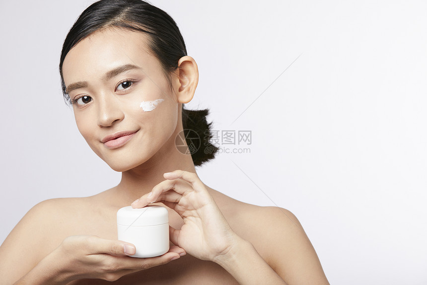展示护肤品面霜的年轻女子图片