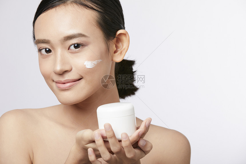 展示护肤品面霜的年轻女子图片