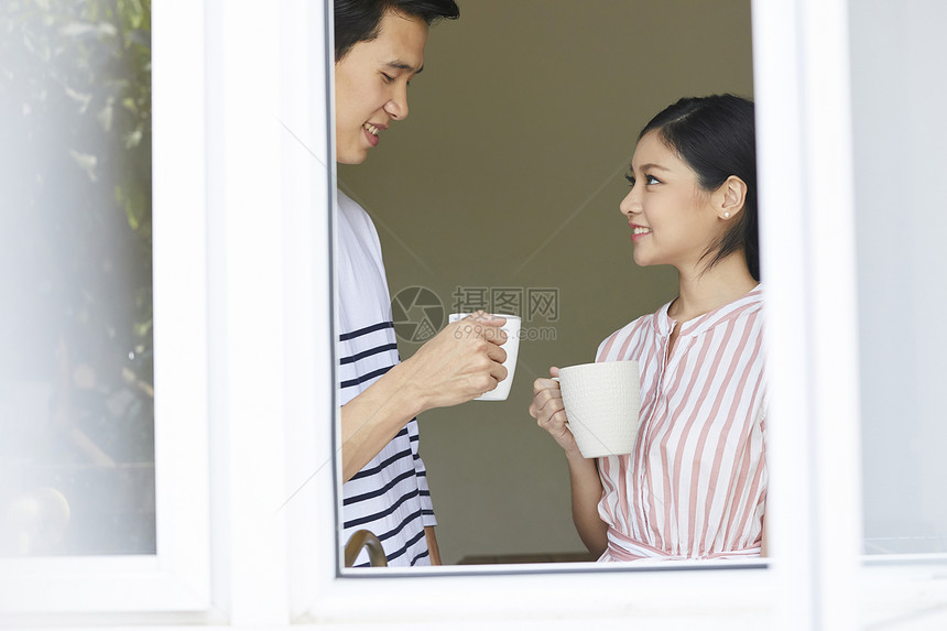 站在窗口聊天的年轻夫妻图片
