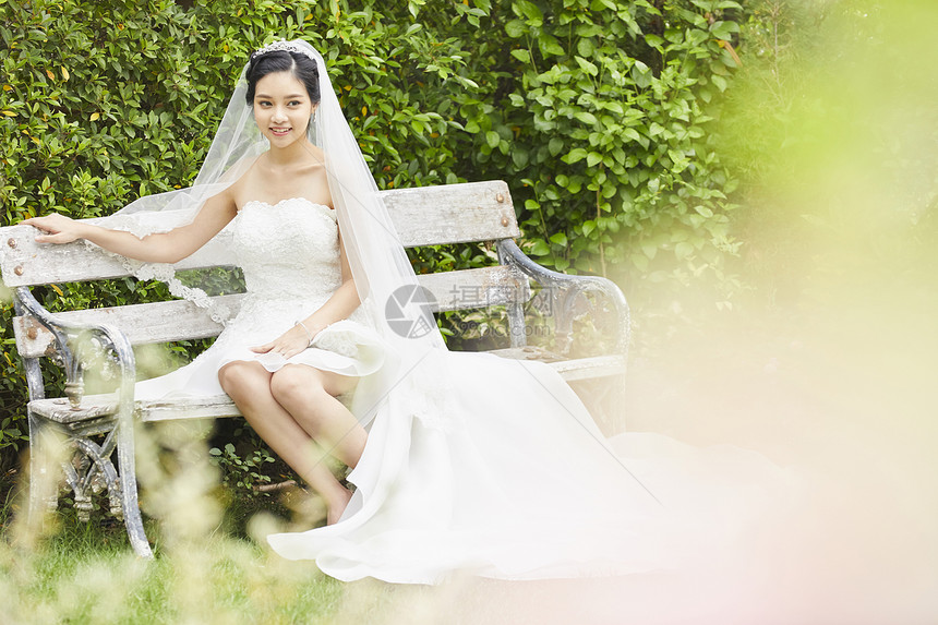 穿着婚纱坐在长凳上的新娘图片