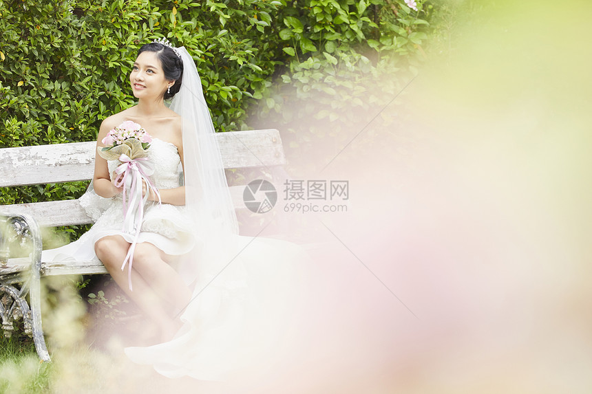 长凳上穿着婚纱拿着手捧花的新娘图片