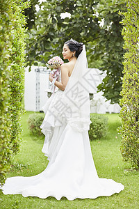 户外婚礼新娘穿着纯白婚纱手拿捧花图片