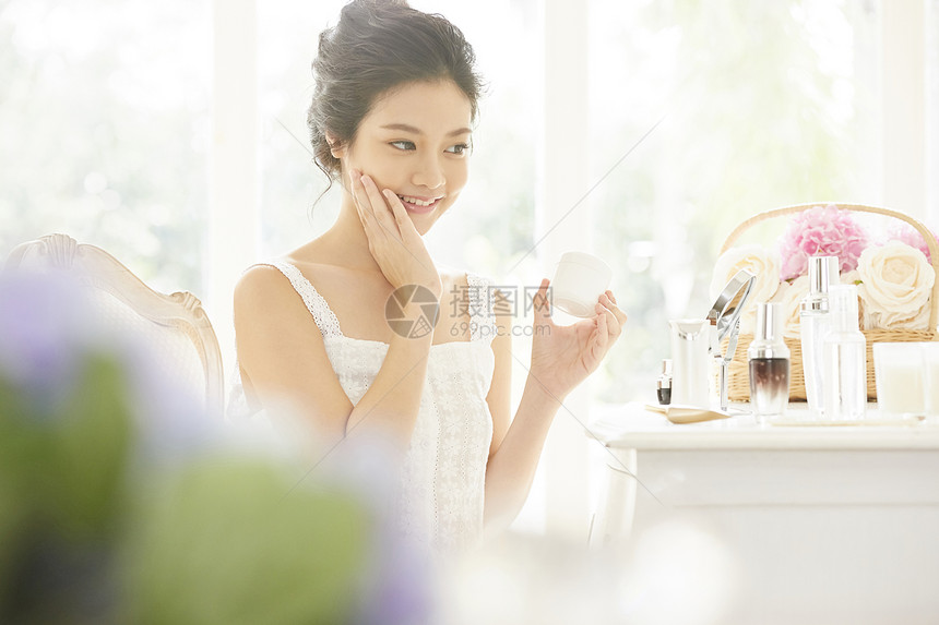 拿着面霜护肤的年轻女子图片