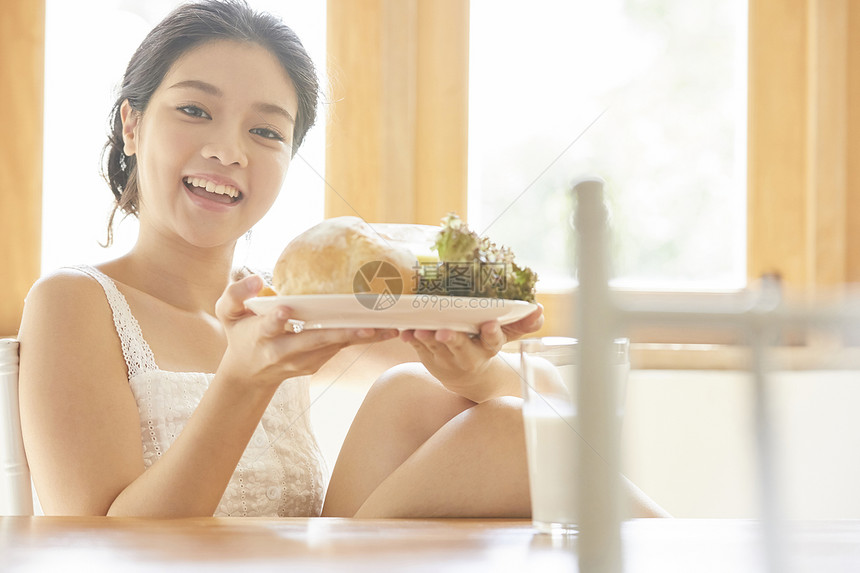 端着早餐微笑的年轻女子图片