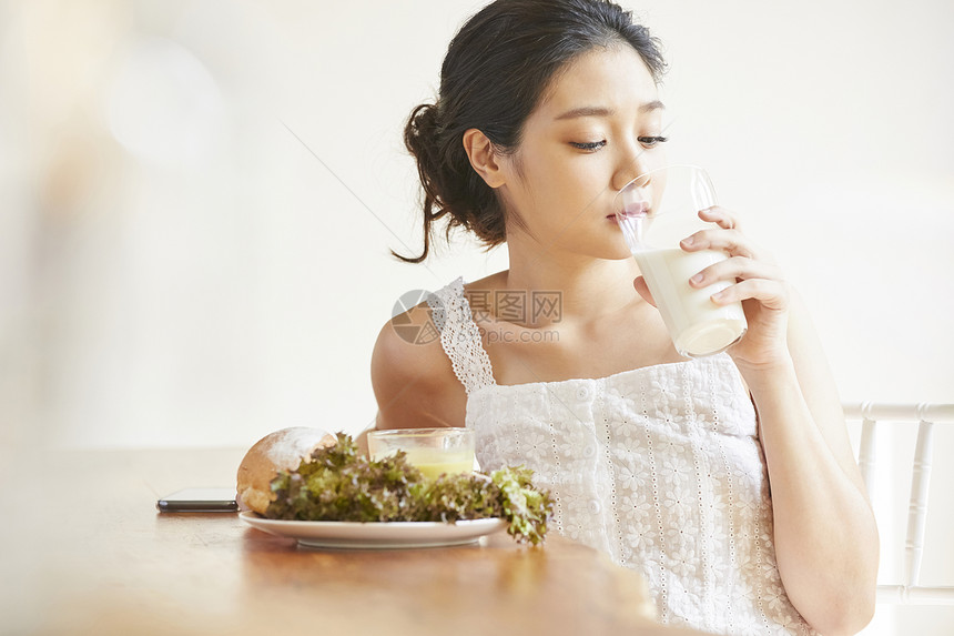 早餐喝牛奶的青年女子图片