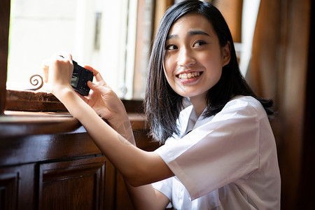 穿校服的女学生在窗边拍照图片