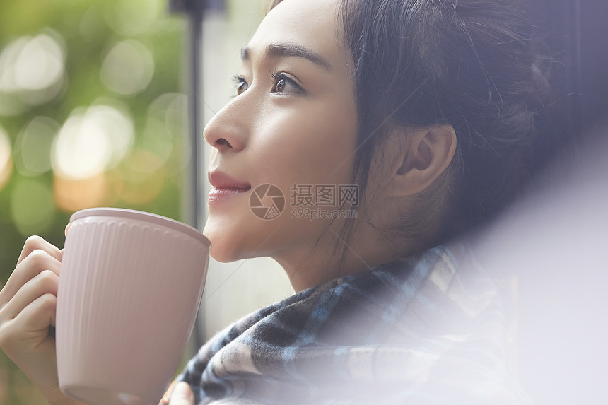 坐在窗边喝茶的年轻居家女性图片