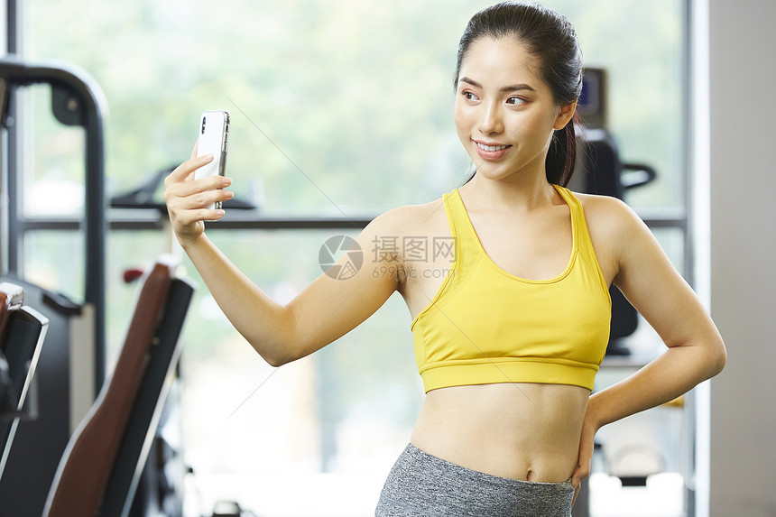健身房拿着手机自拍的年轻女子图片