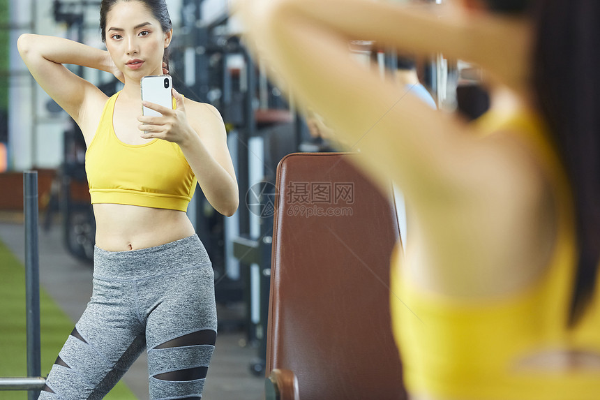 健身房拿着手机拍照的运动女性图片