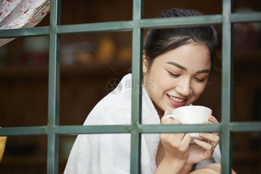 窗边喝水的女性图片